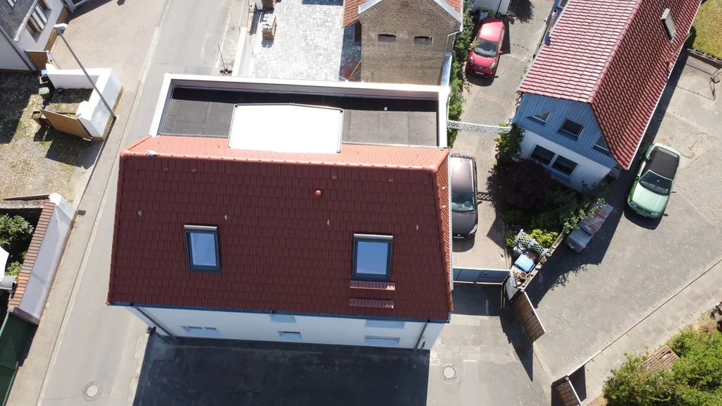 Senkrechte Luftaufnahme eines umgebauten Dachs mit Flachdachanbau